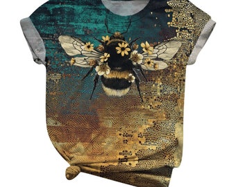 May include: A short-sleeved t-shirt with a colorful abstract design featuring a bee with flowers on its back. The bee is surrounded by a mosaic-like pattern in shades of gold and brown.