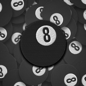 Könnte beinhalten: Nahaufnahme einer schwarzen 8-Ball mit weißen Nähten. Die 8-Ball ist von anderen 8-Balls umgeben, die alle schwarz mit weißen Nähten sind.