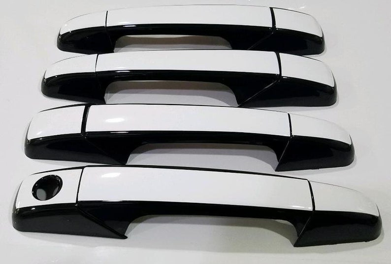 May include: Four black and white car door handles. The handles are made of plastic and have a glossy finish. The handles are designed to replace the original handles on a car.