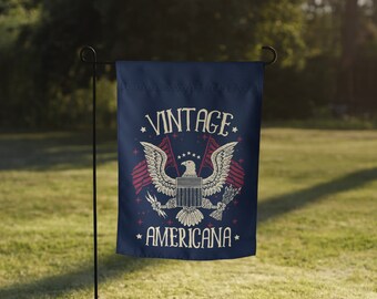 May include: A blue garden flag with a vintage Americana design. It features a bald eagle with outstretched wings holding a banner that says "Vintage Americana".