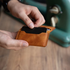 May include: A brown leather wallet with a black card inside. The wallet is open and the card is being pulled out.