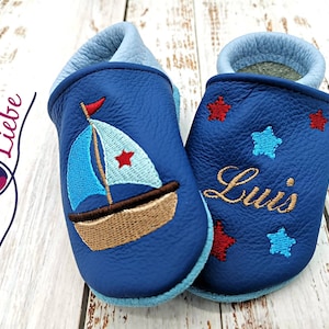 a pair of blue baby shoes with a sailboat on them