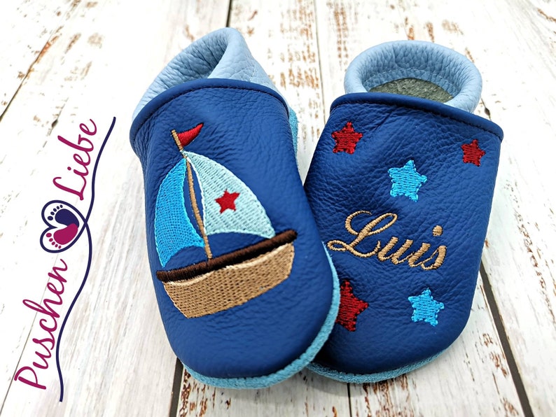 a pair of blue baby shoes with a sailboat on them