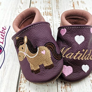 a pair of baby shoes with a horse on them