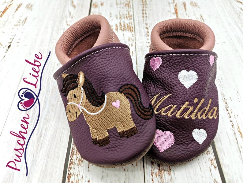a pair of baby shoes with a horse on them