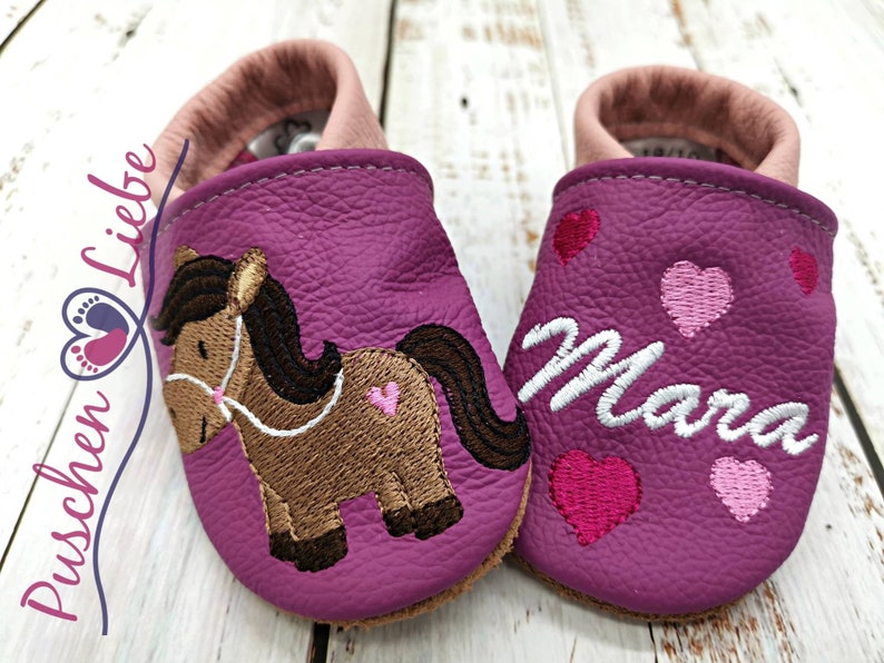 a pair of baby shoes with a horse on them