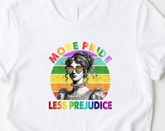 Könnte beinhalten: Weißes T-Shirt mit einer Grafik einer Frau mit regenbogenfarbenen herzförmigen Sonnenbrillen, vor einem regenbogenfarbenen Hintergrund. Der Text "MORE PRIDE LESS PREJUDICE" wird oberhalb und unterhalb des Bildes angezeigt.