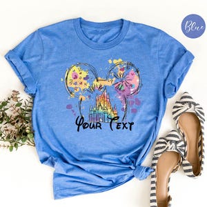 K&ouml;nnte beinhalten: Eine wei&szlig;e Keramik-Tasse mit schwarzem Henkel und dem Text "But First, Coffee" in fetter, schwarzer Schrift. Die Tasse steht vor einem verschwommenen Hintergrund. Die Tasse ist etwa 10 cm hoch.