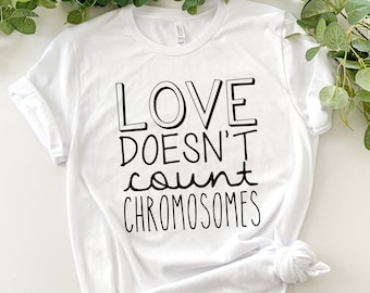 Könnte beinhalten: Weißes T-Shirt mit schwarzem Text, der "Liebe zählt keine Chromosomen" lautet.