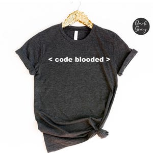 Könnte beinhalten: Dunkelgraues T-Shirt mit dem Aufdruck "< code blooded >" in Weiß.