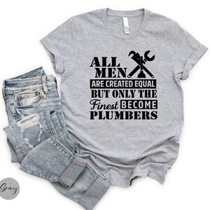 May include: Gray t-shirt with black text that reads "All men are created equal but only the finest become plumbers". The text is accompanied by a wrench and a plunger graphic.
