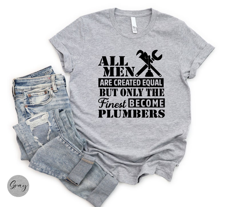 May include: Gray t-shirt with black text that reads "All men are created equal but only the finest become plumbers". The text is accompanied by a wrench and a plunger graphic.
