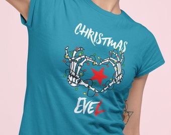 May include: A turquoise blue t-shirt with a white graphic of skeleton hands holding a red star with Christmas lights. The text "Christmas Eve" is printed below the graphic.