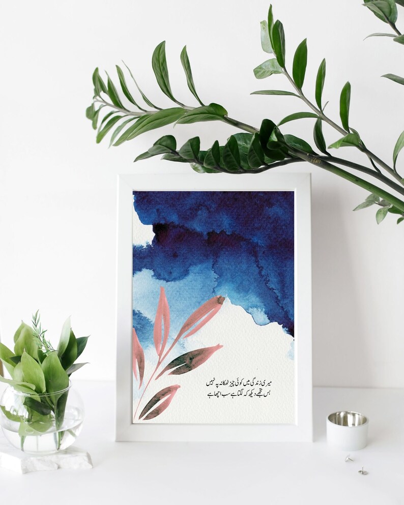 May include: A framed print with a blue watercolour background and a pink floral design. The print features a quote in Urdu script: "میری زندگی میں کوئی چیز ٹھکانہ پر نہیں بس مجھے دیکھ کہ لگتا ہے سب اچھا ہے"