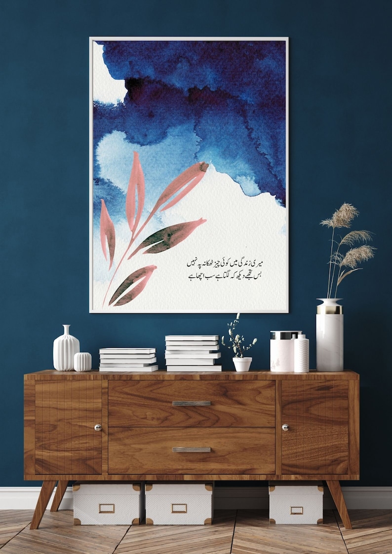 May include: A framed watercolour painting with a blue and white background and a pink floral design. The painting includes a quote in Urdu script: "میری زندگی میں کوئی چیز ٹھکانہ پہ نہیں بس مجھے دیکھ کہ لگتا ہے سب اچھا ہے"