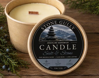 May include: A round, light brown paper container holding a cream-colored candle with a wooden wick. The lid features a black label with the text Stone Gully, Salt & Stone, and a mountain image. It includes the weight 5.1oz / 144g and text Easy Drop In Refill.