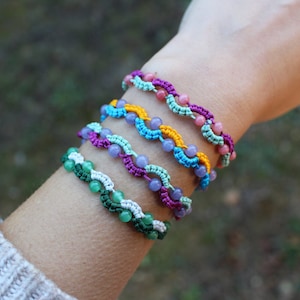 Puede incluir: Cinco pulseras de amistad coloridas con cuentas, que presentan una variedad de colores, incluyendo verde, azul, morado, rosa y amarillo.