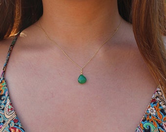 May include: A gold chain necklace with a teardrop-shaped green gemstone pendant.