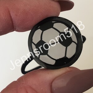 May include: Black hair tie with a white and black soccer ball design.