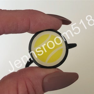 May include: A black hair tie with a white tennis ball design.