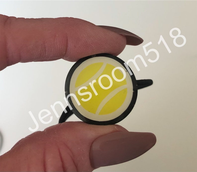 May include: A black hair tie with a white tennis ball design.
