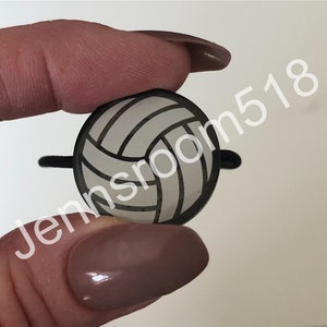 May include: A white volleyball with black seams, shown as a close-up. The volleyball is a small, decorative item.