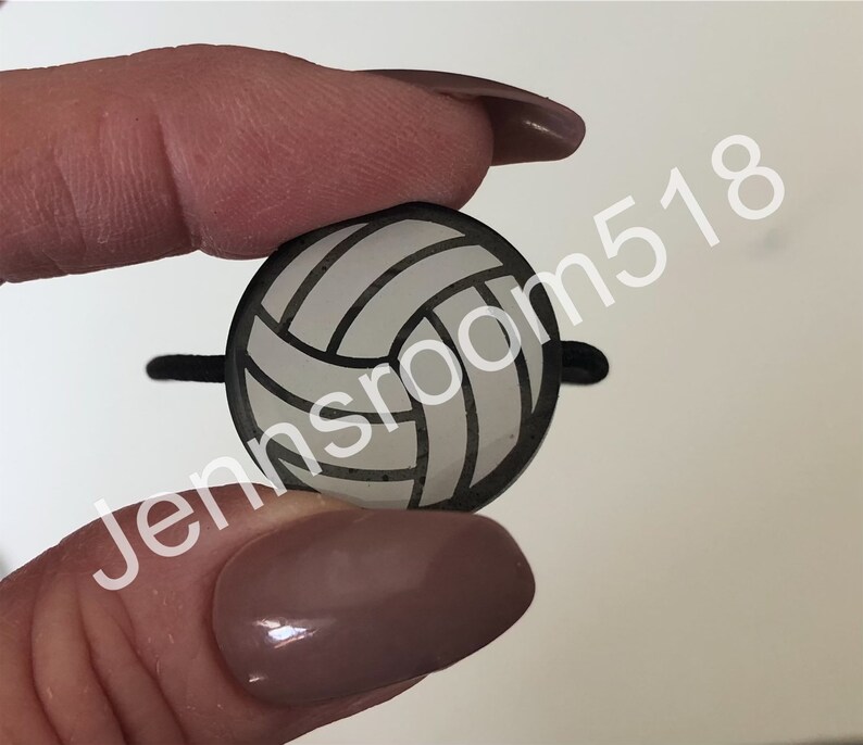 May include: A white volleyball with black seams, shown as a close-up. The volleyball is a small, decorative item.