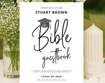 May include: A white Bible guestbook with black script, a graduation cap, and the text "Congratulations Stuart Brown." The book is decorated with white flowers and a candle. The text reads "Class of 2025."