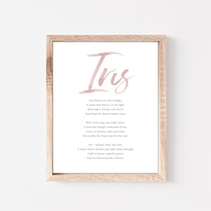 Può includere: Stampa incorniciata con una cornice in legno chiaro. La stampa presenta il nome "Iris" in un morbido carattere acquerello rosa in alto, con una poesia sotto. La poesia è anch'essa rosa, con uno sfondo bianco.