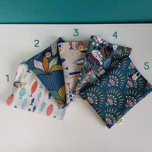 Puede incluir: Cinco bolsas de tela con diferentes patrones. Las bolsas son de color verde azulado, verde y beige con varios patrones que incluyen peces, flores y formas geom&eacute;tricas. Cada bolsa tiene un bot&oacute;n de madera.