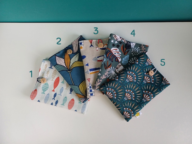 Puede incluir: Cinco bolsas de tela con diferentes patrones. Las bolsas son de color verde azulado, verde y beige con varios patrones que incluyen peces, flores y formas geom&eacute;tricas. Cada bolsa tiene un bot&oacute;n de madera.