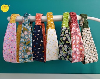 Puede incluir: Una colección de siete diademas de tela con bandas elásticas traseras, que presentan varios patrones que incluyen chispas rosas, flores azules, lunares azul marino, confeti blanco, flores negras, flores rosas y formas geométricas verdes.