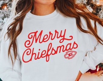 May include: White sweatshirt with red lettering that says "Merry Chiefsmas" with a red Kansas City Chiefs logo.