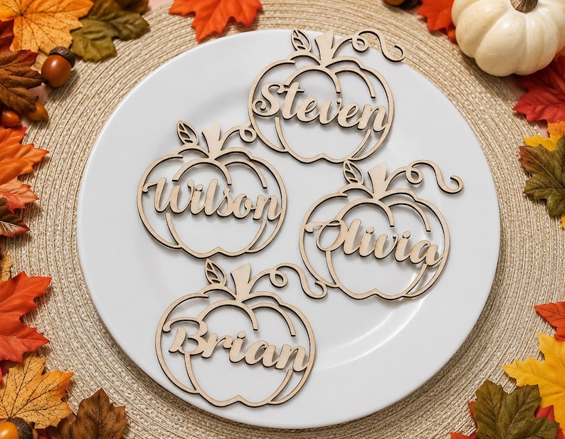 Puede incluir: Cuatro adornos de madera cortados con l&aacute;ser en forma de calabaza, cada uno con un nombre &uacute;nico en letra cursiva: Steven, Wilson, Olivia y Brian. Estos recortes de madera clara tienen forma de calabaza con tallos y zarcillos.