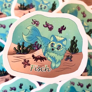 Puede incluir: Una pegatina con un zorro de dibujos animados con cola de sirena bajo el agua. El zorro es azul y verde, rodeado de peces, algas, un cangrejo y una estrella de mar. La palabra "Fisch" está escrita en verde.