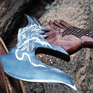 May include: A black axe with a dragon design etched into the blade. The axe has a wooden handle with a carved dragon design and a black leather wrap.