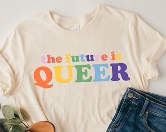 May include: A cream-colored t-shirt with the text "the future is QUEER" in rainbow colors.
