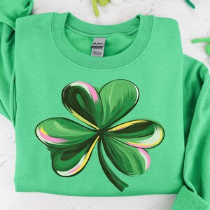 May include: A green sweatshirt with a colorful shamrock design. The shamrock is made up of swirls of green, pink, and yellow.