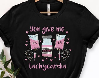 May include: Black t-shirt with a pink graphic of three IV bags and a vial of medicine. The text "You give me tachycardia" is printed below the graphic.