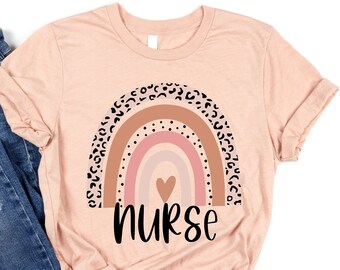 May include: A pink t-shirt with a rainbow design featuring a heart and leopard print accents. The text "nurse" is printed below the rainbow.