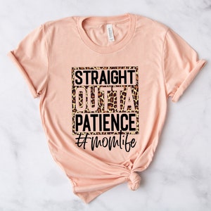 Op de afbeelding: Perzikkleurige T-shirt met een zwarte vierkante afbeelding met de tekst "Straight Outta Patience #momlife" met een luipaardprint achtergrond.