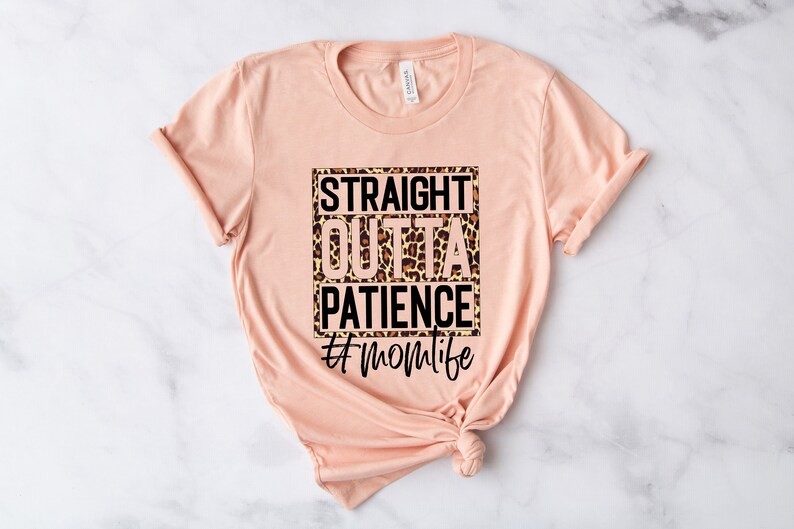 Op de afbeelding: Perzikkleurige T-shirt met een zwarte vierkante afbeelding met de tekst "Straight Outta Patience #momlife" met een luipaardprint achtergrond.