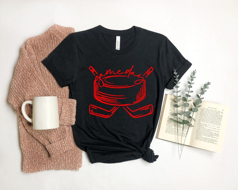 May include: Black t-shirt with a red graphic of a hockey puck and two hockey sticks. The text "game day" is written above the puck.