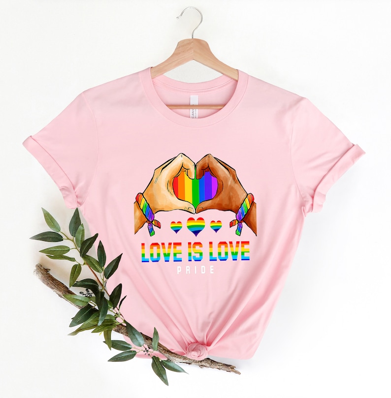 May include: Pink t-shirt with a rainbow heart design and the text "Love is Love Pride".