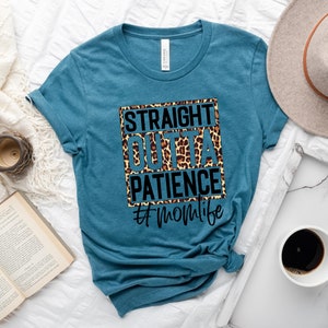 Op de afbeelding: Een tealblauw t-shirt met een zwart-witte afbeelding met de tekst "Straight Outta Patience #momlife". De afbeelding is op een luipaardprint achtergrond.
