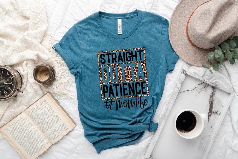 Op de afbeelding: Een tealblauw t-shirt met een zwart-witte afbeelding met de tekst "Straight Outta Patience #momlife". De afbeelding is op een luipaardprint achtergrond.