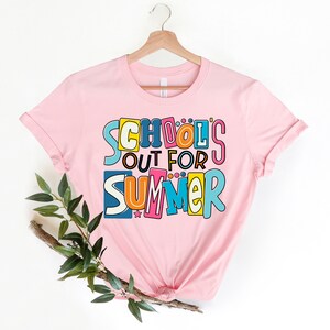 May include: Pink t-shirt with a colorful graphic that says "School's Out For Summer".