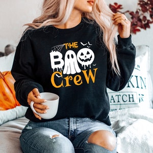 May include: Black sweatshirt with a white ghost and pumpkin graphic and the text "The Boo Crew".