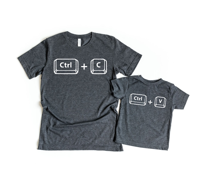 May include: Two heather grey t-shirts with a white graphic of computer keyboard keys. The larger shirt has the text "Ctrl + C" and the smaller shirt has the text "Ctrl + V".