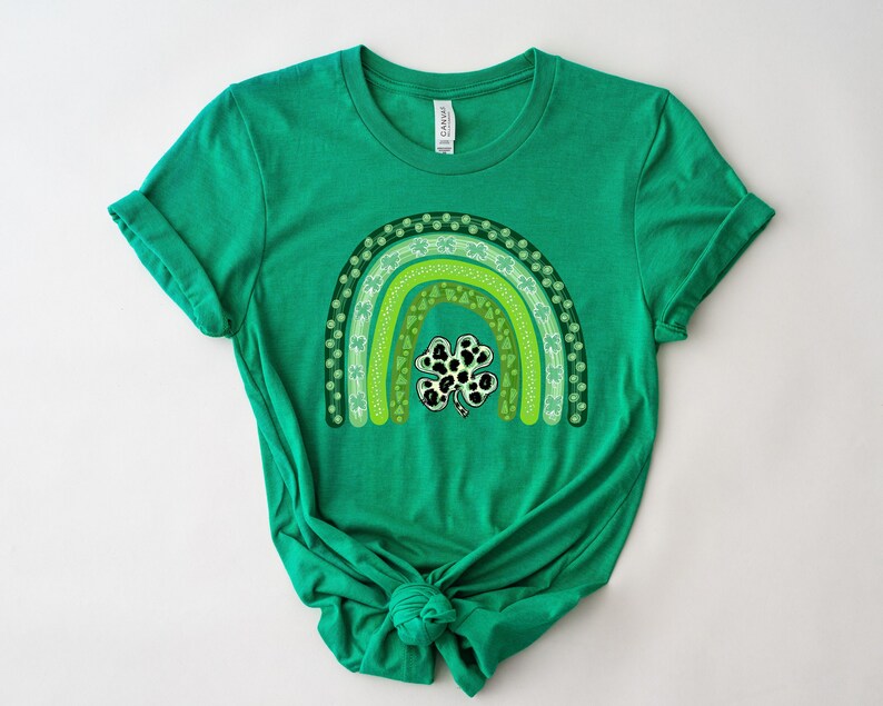 May include: Green t-shirt with a rainbow design made of shamrocks and a black and white shamrock in the center.